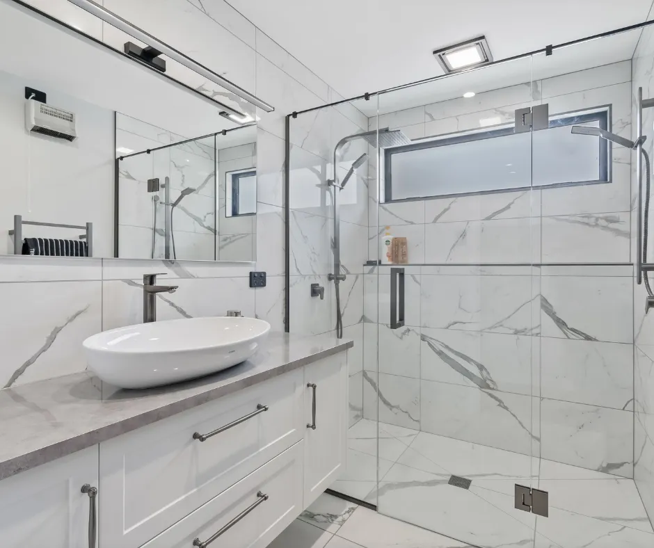 Completed bathroom with full-height marble tiling and a frameless shower