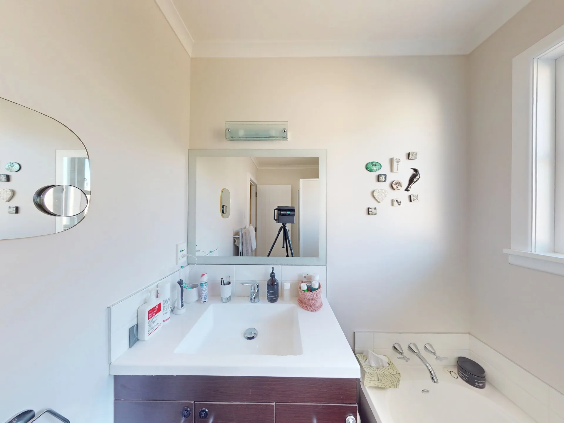 The existing bathroom before work started: dark timber vanity, square mirror and a corner bath under the window