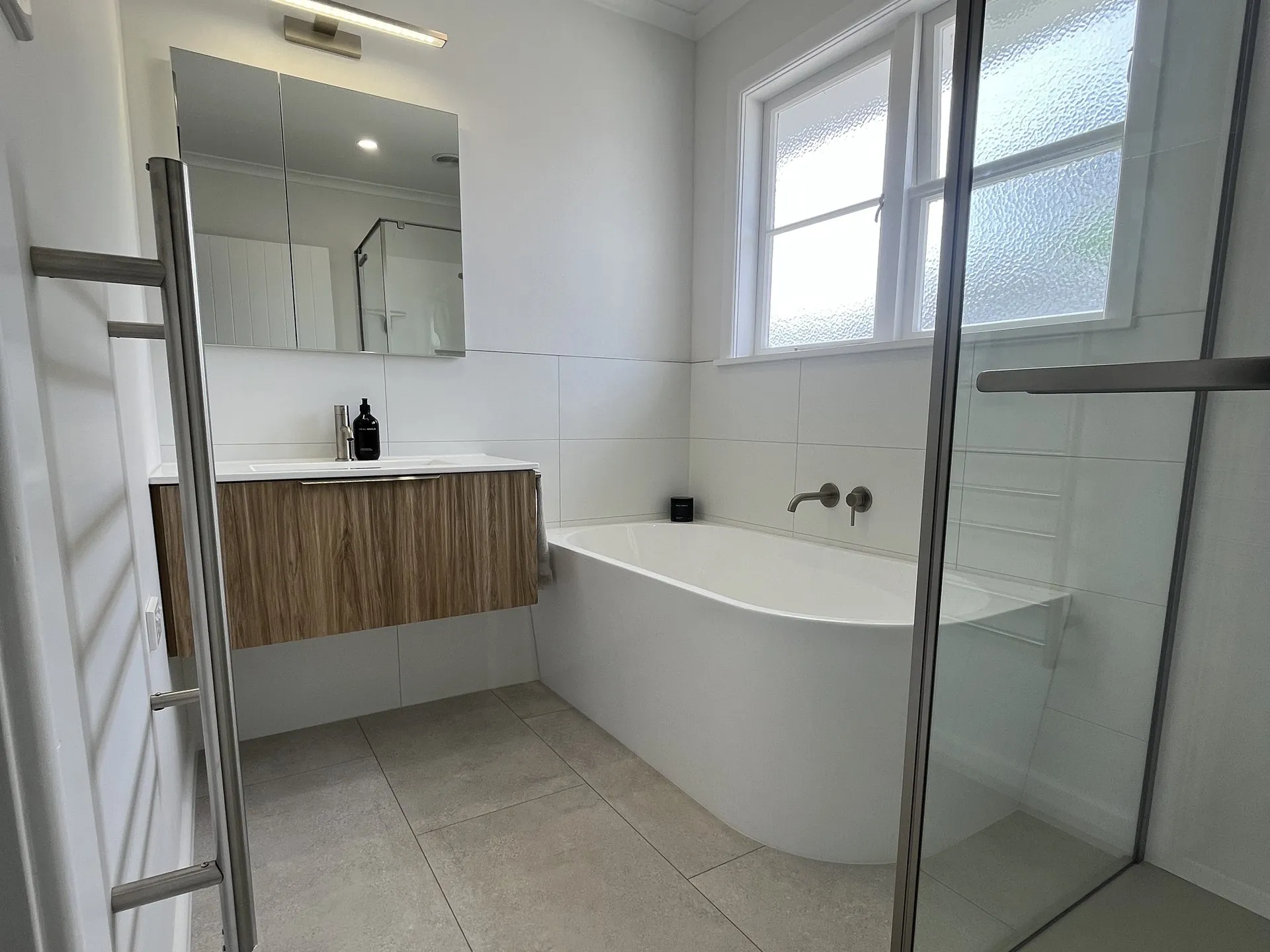 The finished bathroom, built to the concept: timber vanity, freestanding bath and framed shower
